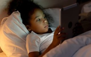 Child using tablet in bed when they should be asleep.