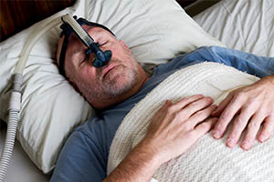 central sleep apnea - man sleeping with CPAP mask