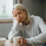 Tired woman holding coffee at table
