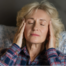 Tired woman in bed with headache